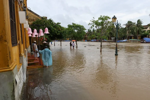 Hoi An, Vietnam, 17 Ekim 2021: Vietnam, Hoi An 'da Thu Bon nehrinin yanındaki sel basmış bir sokakta birkaç kişi