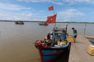 Hoi An, Vietnam, 30 Ekim 2021 Duy Hai balıkçı limanındaki bir rıhtımda demirlemiş bir tekneden iki adam kutuları boşaltıyor. Thu Bon nehri ağzı. Hoi An, Vietnam