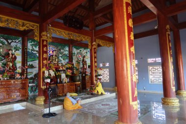 Hoi An, Vietnam, 20 Kasım 2021: Chua Nhon An Tapınağı 'nın üst dua salonunda sunağın yanında dua eden iki Budist keşiş. Hoi An, Vietnam