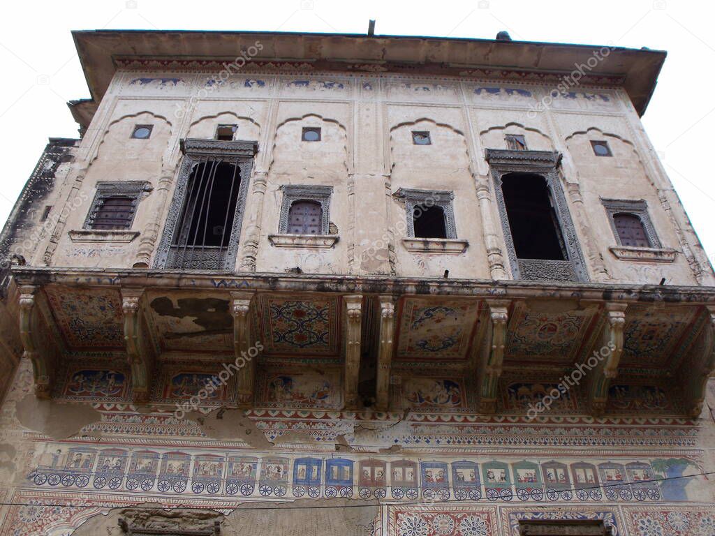 Mandawa, Rajasthan, India, August 11, 2011: Windows and drawing of a train on the facade of an old palace or haveli in Mandawa, Rajasthan, India