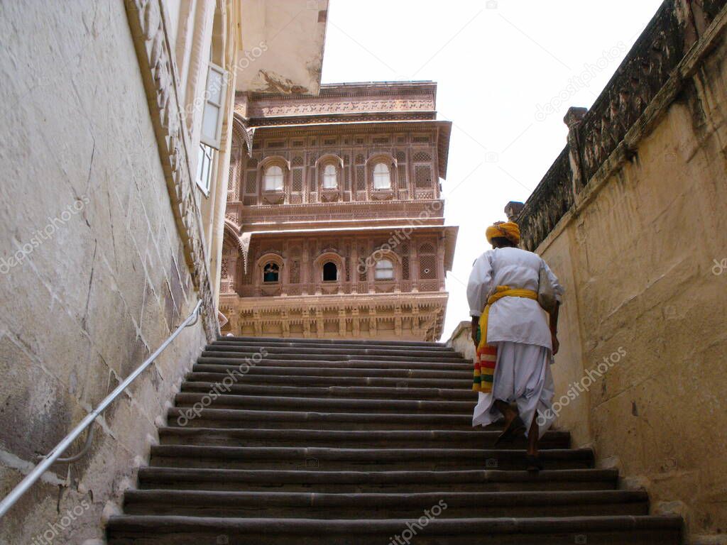 Jodhpur, Rajasthan, India, August 14, 2011: A man in traditional clothes walks up the stairs of the Mehrangarh Fort in the blue city of Jodhpur, India