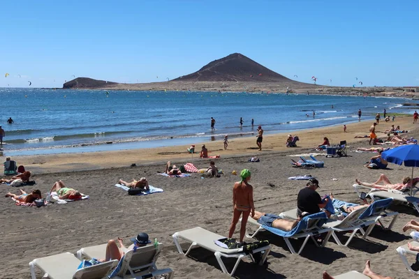 El Medano, Tenerife, İspanya, 8 Mart 2022: Birçok turist arka planda Kızıl Dağ ile birlikte El Medano 'nun volkanik kumsalında güneşlenir ve yıkanır. Tenerife, İspanya