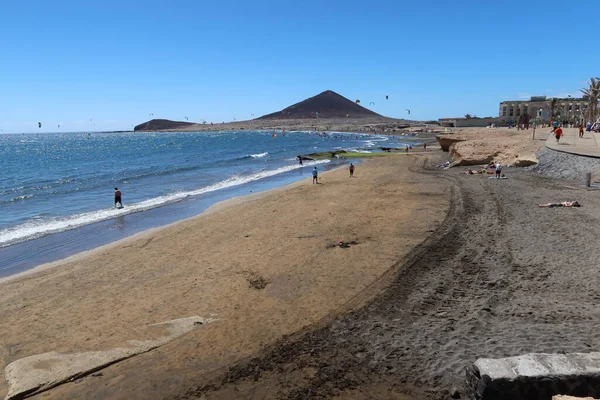 El Medano, Tenerife, İspanya, 8 Mart 2022: El Medano 'nun volkanik kumsalındaki insanlar ve arka planda Kızıl Dağ. Tenerife, İspanya