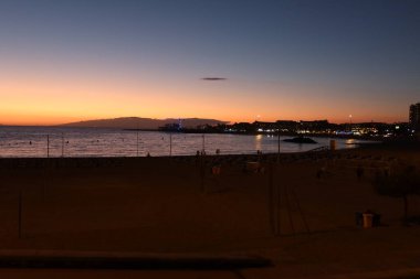 Los Cristianos plajı, Tenerife, İspanya, 23 Şubat 2022: Los Cristianos plajında volkanik kumlarla gün batımı, Los Cristianos, Tenerife, İspanya