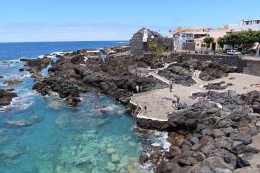 Garachico, Tenerife, Canary Islands, Spain, July 6, 2022: Tourists at the El Caleton natural pools next to the San Miguel castle in Garachico, Tenerife. Spain