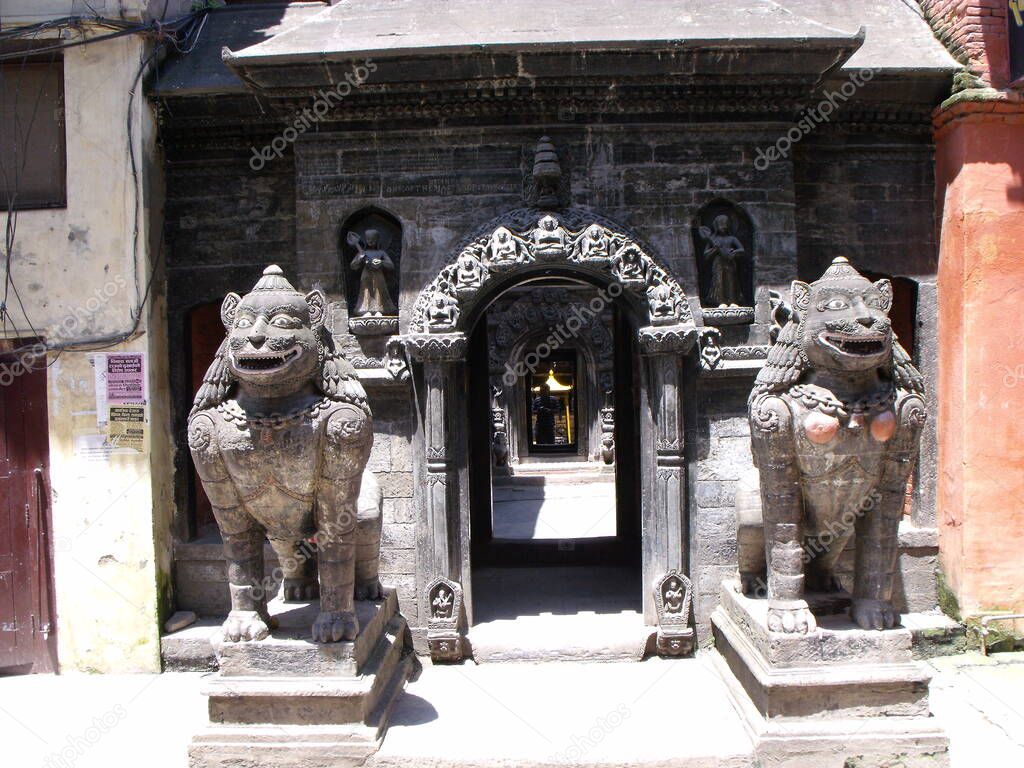 Patan, Kathmandu, Nepal, August 20, 2011: Two stone lions at the entrance gate of Hiranya Varna Mahavihar. Golden temple. Patan, Kathmandu. Nepal