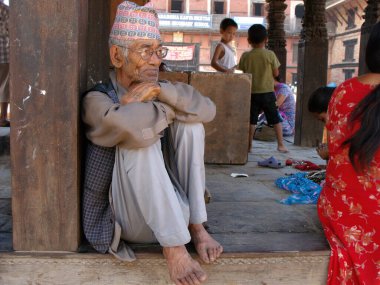 Durbar Square, Patan, Kathmandu, Nepal, August 20, 2011: An elderly man sitting on a wooden porch in Durbar Square, Patan, Kathmandu, Nepal