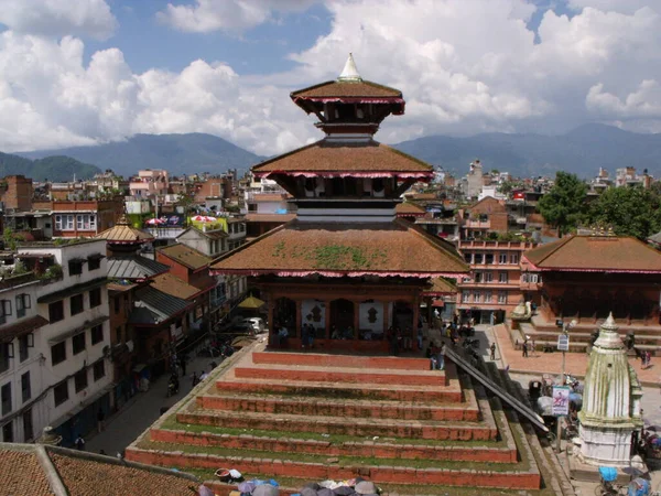 Kathmandu, Nepal, August 20, 2011: Old wooden building with mountains in the background in a square in Kathmandu. Nepal
