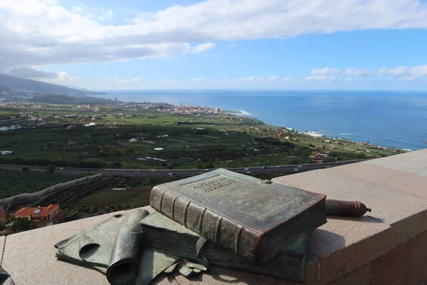 La Orotava, Tenerife, Spain, February 23, 2022: Sculpture of the treatise by the German naturalist Alexander Von Humboldt at the Humboldt viewpoint with Puerto de la Cruz in the background. La Orotava, Tenerife. Spain