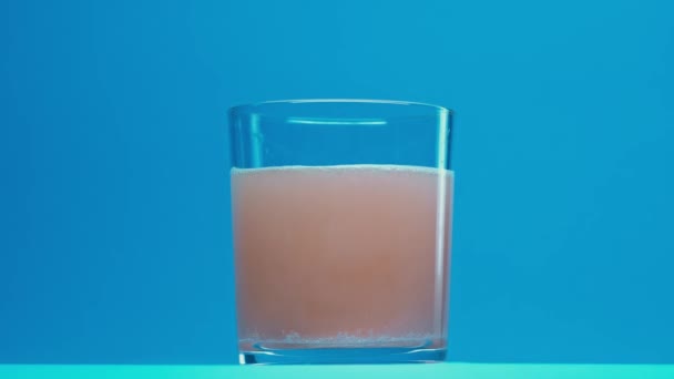 Sparkling Pill Changes Color Water Glass Blue Background — Stock video