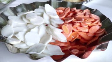 Cleanly cut radish and carrot are decorated to be eaten in the form of salad.