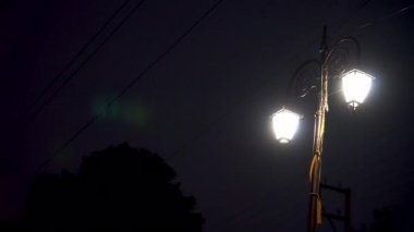 Gece karanlığında yanan sokak fenerleri karanlık sokaklara ışık saçıyor.