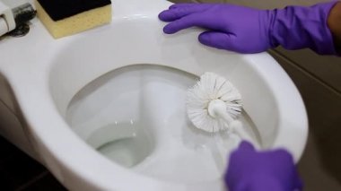 Genç adam tuvalette klozet temizliyor.