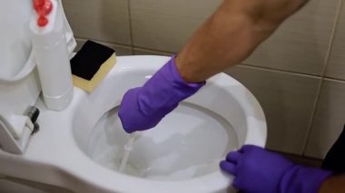 Lastik eldivenli adam tuvaleti yıkayacak.