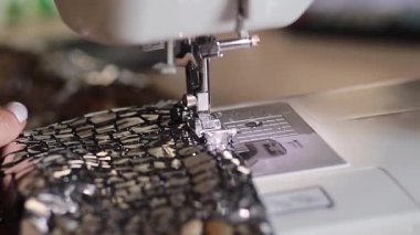 Terzi kadın dikiş makinesinde elbise dikiyor, elleri yakın. Atölyede ya da atölyede dikiş işlemi. Elbise, sütyen, sütyen, sütyen, sütyen. Serbest çalışan..