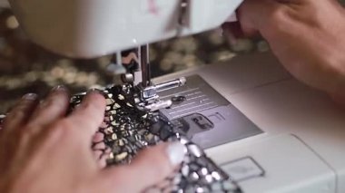 Dikiş makinesiyle kumaşı dikerken parmaklarının makro kaydı.