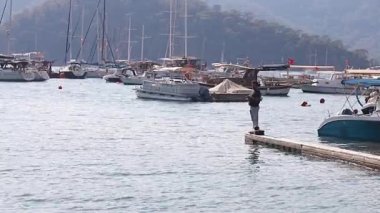 Güneşli bir yaz günü. Olta kamışlı erkek balıkçılar, arka planda yatlarla balık avlıyorlar. Popüler turizm merkezi. Türkiye