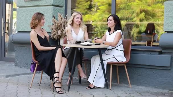 三个快乐的女性朋友坐在路边咖啡馆的桌旁 谈笑风生 身体积极的女人喜欢友好的谈话和鸡尾酒 — 图库视频影像