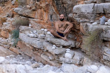 Denge taşları, meditasyon, doğa ile bağlantı, dinlenme ve rahatlama ile çevrili bir dağda oturan adam yogi..