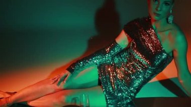 Güzel, ince, parlak makyajlı, eski tarz saç kesimi olan, gümüş rengi parlak bir arka planda gümüş rengi elbisesi olan sarışın bir kız. Güzellik, moda, bayram, tebrik, hediyeler, kutlama, gümüş rengi..