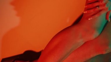 Model aşağı bakıyor ve gümüş elbiseyle flört ediyor. Gri arka plandaki stüdyoda gümüş rengi kısa elbise ve parlak ayakkabılar giyerek flört eden güzel bir manken. Uzun bacakları mükemmel.