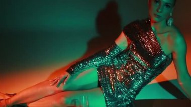 Esmer saçlı, seksi beyaz kadın gece partisinde barın içinde renkli ışıkla eğleniyor. Şarabı olan güzel bir kız. Gümüş pullu kadın elbisesi