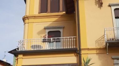 Como Gölü yakınlarındaki küçük bir Avrupa-İsviçre kasabasının dar sokaklarının harika panoramaları. Renkli evler. Video hareket halinde. Mavi gökyüzü. Eski evler ve sokaklar. Bayrak. İTALYA, Como