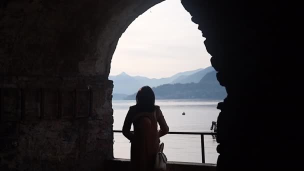 墙上的女人在黑暗的拱门里轮廓女孩在明亮的背景天空和水 意大利科莫 — 图库视频影像