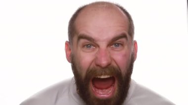 Stüdyoda bağıran öfkeli adamın portresi. Öfkeli adam beyaz arka planda bağırıyor. Agresif yüz ifadesi olan bir erkek. Kameraya yavaş çekimde bağıran kızgın model.