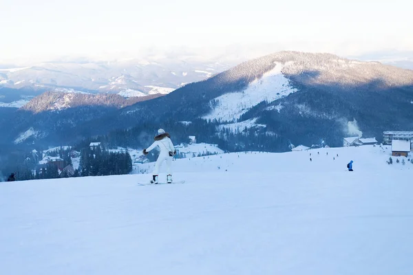 レジャー スポーツ 人々の概念 雪の背景にスキー帽をかぶった山々 雪の山のショーで手にスノーボードと赤いスキースーツの魅力的なブロンド スキー休暇 — ストック写真