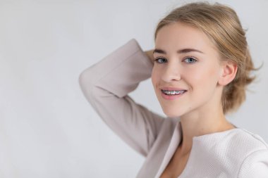 Beyaz arka planda Noel süveteri giymiş, elinde görünmez bir diş teli tutan ve baş parmağını kaldıran genç beyaz bir kız bu yeni tedaviyi öneriyor. Diş sağlığı konsepti