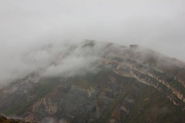 Rusya 'nın Ural Dağı' nın tepesindeki haşin dağ manzarası. Kayalar sis bulutlarıyla kaplı.