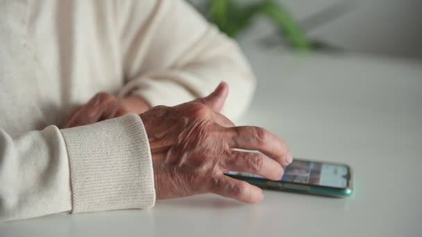 Emerytka Ciepłych Ubraniach Pomarszczonymi Rękami Siedzi Przy Stole Ogląda Zdjęcia — Wideo stockowe