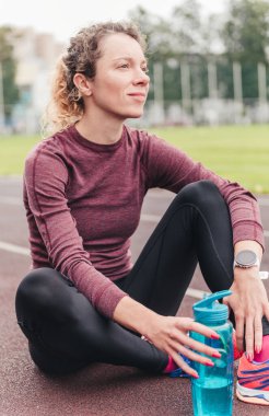 Şişeli ve akıllı kadın stadyumda oturuyor.