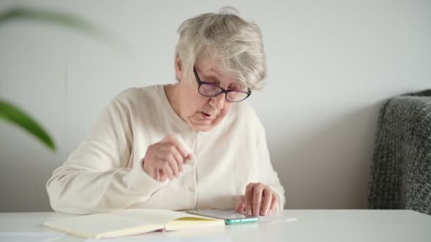 Elderly woman calculates monthly budget with interest — Stock Video