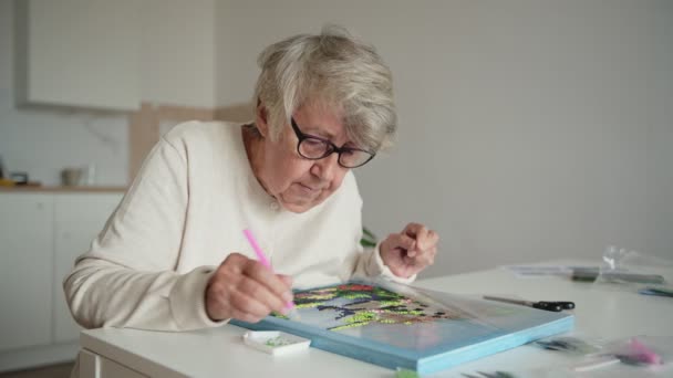 Stará žena tráví čas odchodu do důchodu kladením diamantové mozaiky — Stock video