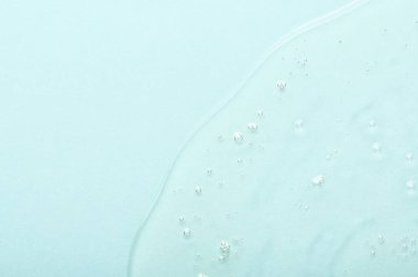 Küçük hava kabarcıkları olan yaşlanma önleyici serumu arka planda hafif turkuaz arka plana döküldü. Dermatolojik prosedürler