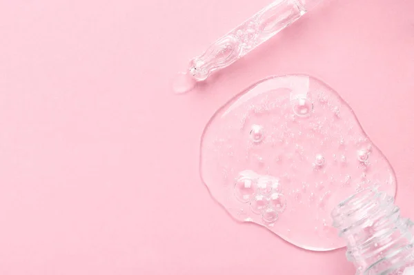 Маленькая бутылка и стеклянная пипетка с прозрачным гелем на светло-розовый — стоковое фото