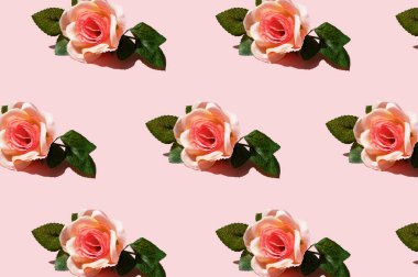 Çiçek desenli, pembe arka planda yeşil yapraklı gül çiçekleri yukarıdan yakından görünüyor. Tebrik kartı tasarımı ayrıntıları