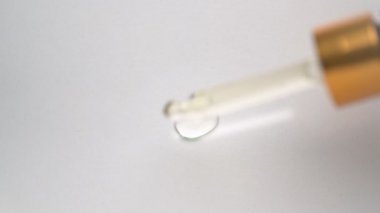 Pipetten temiz yüzeye şeffaf bir serum damlıyor. Hiyalüronik asit içerir.