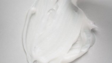Yumuşak vücut kremi damlacıkları, yukarıdan beyaz yüzey manzarası üzerinde fırçalanır. Güzellik ve refah için kozmetik ürünü