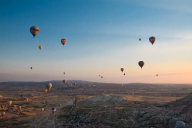 Kapadokya 'nın tuhaf dağları arasında gün doğumunda yükselen inanılmaz balonlar.