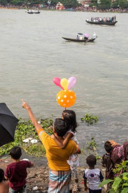 Nehir kenarındaki tekne yarışı izleyicisi eğleniyor. Bu görüntü Eylül-28-2021 'de Dhaka, Burigongga nehri, Bangladeş, Güney Asya' dan çekildi.