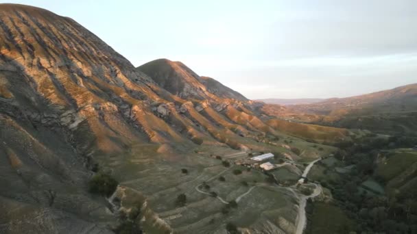 Picos de montanha nos raios do sol poente, vista aérea, uma aldeia no cânion — Vídeo de Stock