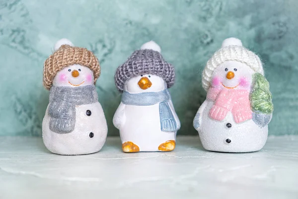 三个陶瓷新年玩具，一个企鹅和雪人，头戴针织帽子和围巾 — 图库照片