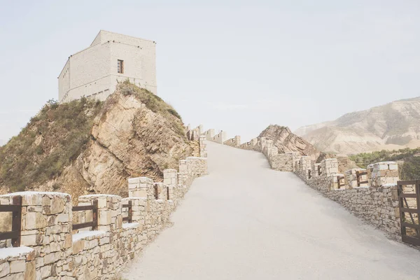 Sebuah jalan dengan pagar batu akan sampai ke menara tua di puncak gunung. Stok Foto
