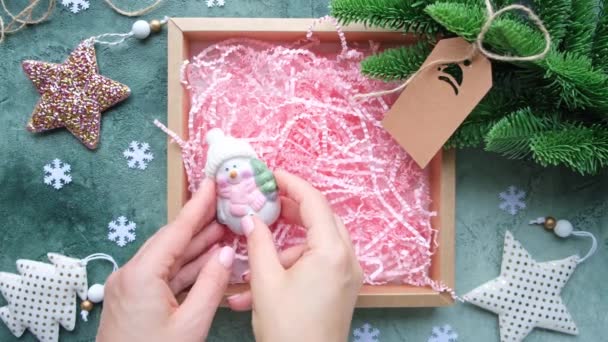 Mãos colocando brinquedos de Natal em uma caixa de presente. Decoração de Ano Novo, envoltório de presente DIY. — Vídeo de Stock