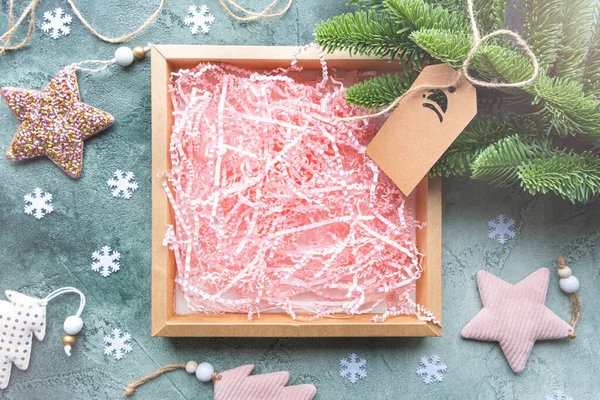 Kotak hadiah kosong dengan kertas merah muda yang diisi dengan latar belakang hijau dengan dekorasi Natal. Stok Lukisan  