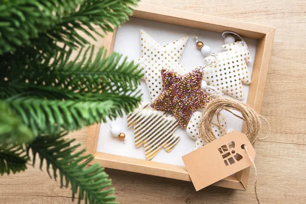Kotak hadiah dengan mainan Natal terbuat dari kain, cabang cemara di latar depan. Stok Gambar
