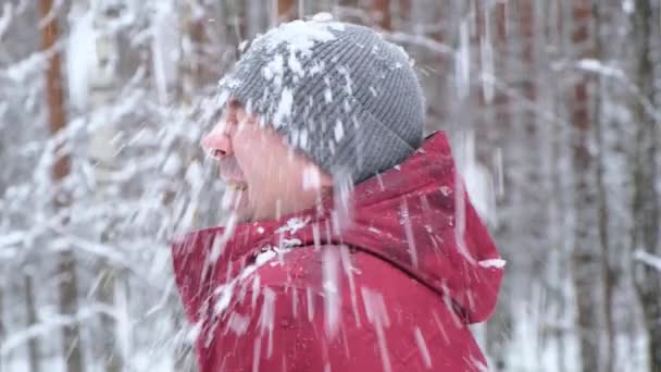Porträtt av en skrattande ung man njuter av snöfall i en park eller skog — Stockvideo